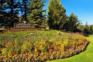 A sign for Arrowhead Country Club of the Rockies surrounded by a vibrant flower garden.