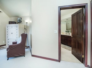 A room with a brown chair, a white dresser, and a wooden door leading to another room. - Charlie Rentz: Arrowhead Ski-In/Out, Steps to Lift, Sleeps 8, Heated Pool + Hot Tub (Edwards)