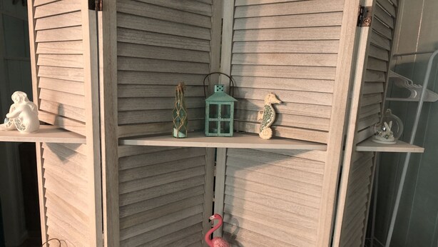 A corner shelf unit with decorative items including a flamingo, a lantern, and small figurines.