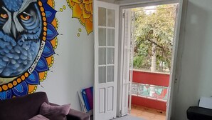 Una sala de estar con un sofá morado, una mesita redonda y un mural de pared colorido.