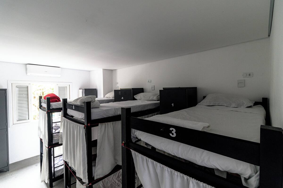 Une chambre de dortoir avec des lits superposés, des lits numérotés et un petit bureau.