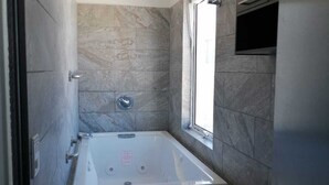 Un bany modern amb una banyera autònoma, un vàter i una finestra que deixa entrar llum natural.