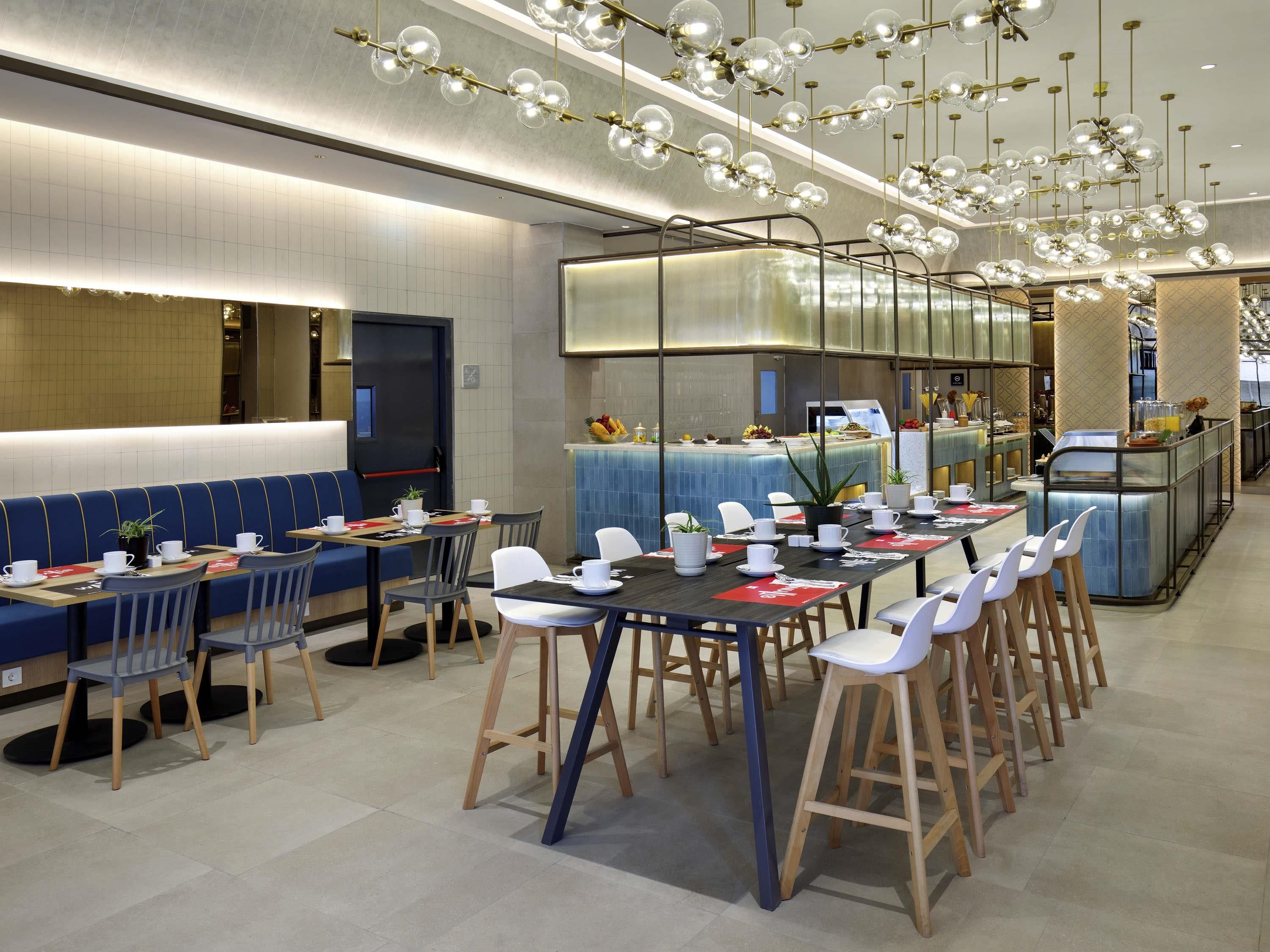 A modern restaurant with high tables, chairs, and a bar area.