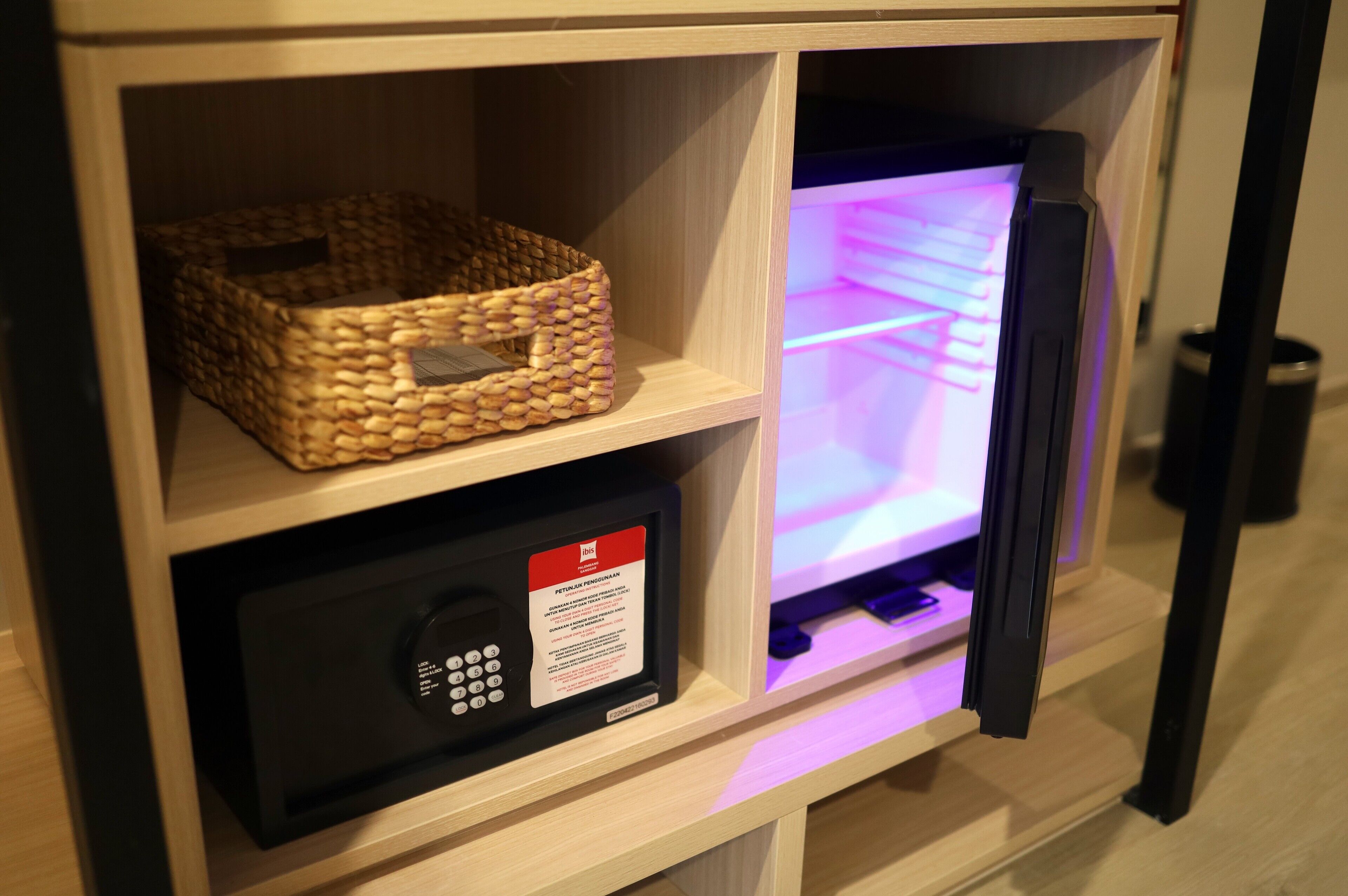 A wooden shelf with a woven basket and a black electronic device with a red label.