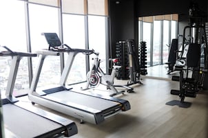 Un gimnasio con cintas de correr, bicicletas estáticas y máquinas de pesas.