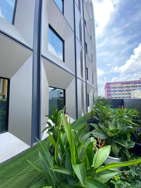 A modern building with large windows and a rooftop garden with various plants. - Ibis Palembang Sanggar (Palembang)