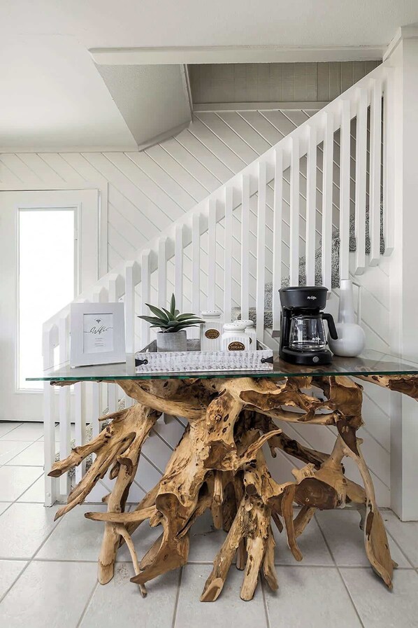 A modern kitchen with a glass coffee table, white cabinetry, and a wooden coffee table with a unique design.