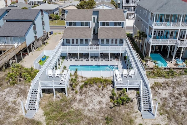 Ein Strandgrundstück mit zentralem Pool, mehreren Terrassen und einem Zugangsweg zum Strand.