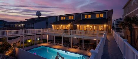 A multi-story building with a swimming pool and a covered deck area.