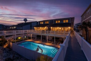 A multi-story building with a swimming pool and a covered deck area.