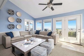 A modern living room with a beige sectional sofa, a marble coffee table, and a ceiling fan.