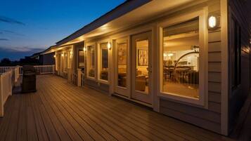 A wooden deck with a covered outdoor area, including a seating area with tables and chairs.