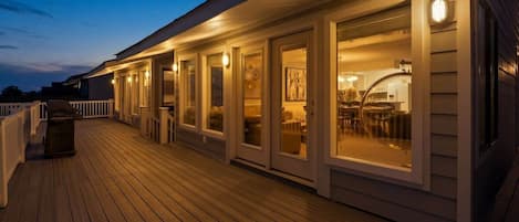 A wooden deck with a covered outdoor area, including a seating area with tables and chairs.