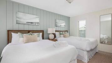 A hotel room with two beds, a large mirror, and a window with blinds.