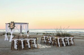 A beach wedding setup with wooden chairs and a white canopy. - Oceanfront, Pool, GolfCart, & Free EV Charger! (Ocean Isle Beach)