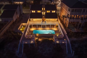 A two-story building with a swimming pool, multiple balconies, and a covered deck area with seating.