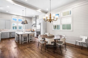 A spacious kitchen with white cabinetry, a central island, and a chandelier.