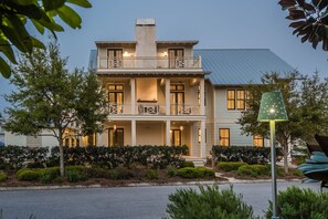 A two-story building with a balcony on the second floor, a covered porch on the first floor, and a green street lamp in the foreground.