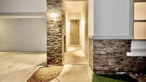 Una casa moderna con facciata in pietra, un garage e un corridoio interno ben illuminato.