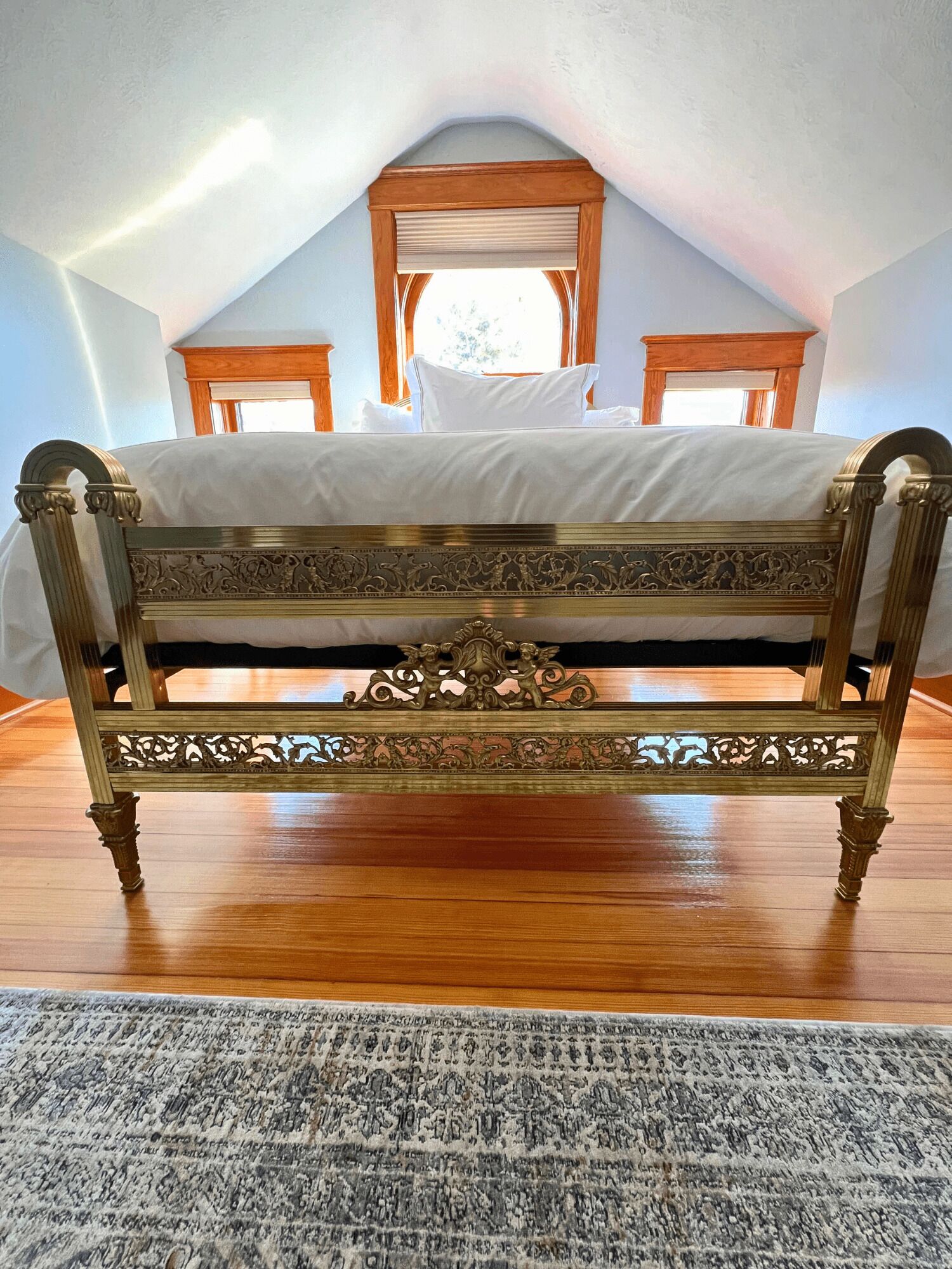 Un dormitorio con una cama grande, un cabecero de madera, una ventana con vistas y suelo de madera.