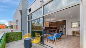 A modern house with a patio area featuring yellow chairs and a blue sofa. - StayCentral - Prahran Penthouse - Mount St, Prahran - 2 Bedrooms, 2 Beds, 2 Bathrooms, 1 secure parking spot and a permit for street parking. (Prahran)