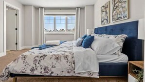 Une chambre à coucher avec un lit, une fenêtre avec des rideaux et deux œuvres d’art accrochées au mur.