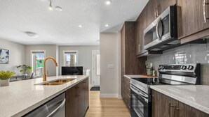 Une cuisine moderne dotée d’appareils électroménagers en acier inoxydable, de meubles en bois et d’un grand îlot central avec un évier.