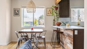 Eine moderne Küche mit einer Holztheke, Barhocker und einer Hängeleuchte.