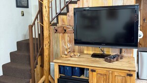 A wooden entertainment center with a flat-screen TV, a clock, and a fireplace below. - Bell's Greer Hideaway (Greer)