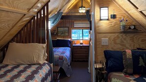A cozy attic bedroom with a sloped ceiling, a ceiling fan, a window with a view, and a small desk area. - Bell's Greer Hideaway (Greer)