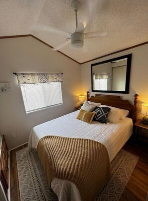 Relax in this serene bedroom with a large bed, bedside tables, and a ceiling fan.