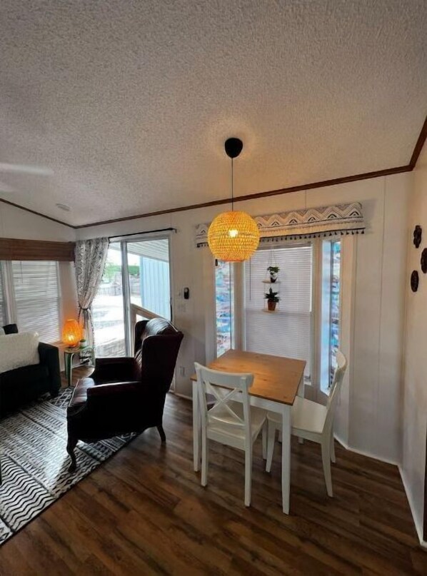 Relax in this inviting living room with a dining area, comfortable armchair, and natural light pouring in through the window.