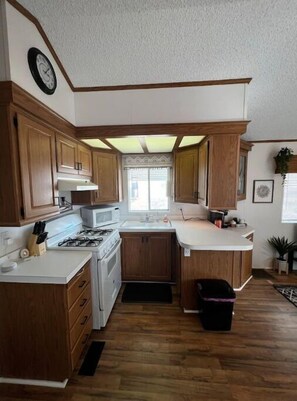 Kitchen features a stove, oven, and sink with a mounted clock.
