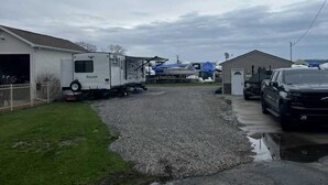 A residential area with a gravel driveway, a white mobile home, and a black pickup truck parked on the street. - Lake St Clair Waterfront (Chesterfield)