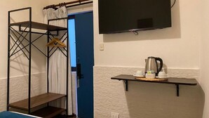 Une chambre avec un lit superposé, un téléviseur fixé au mur et une étagère avec une machine à café et des tasses.