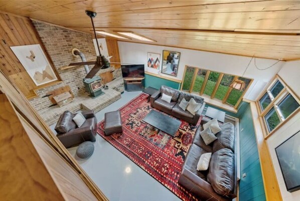 Un salon chaleureux avec une cheminée, des canapés en cuir et un tapis à motifs.