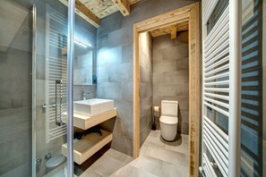 A modern bathroom with a glass shower enclosure, a wooden vanity, and a separate toilet area. - Espectacular Casa en Baqueira (Baqueira)