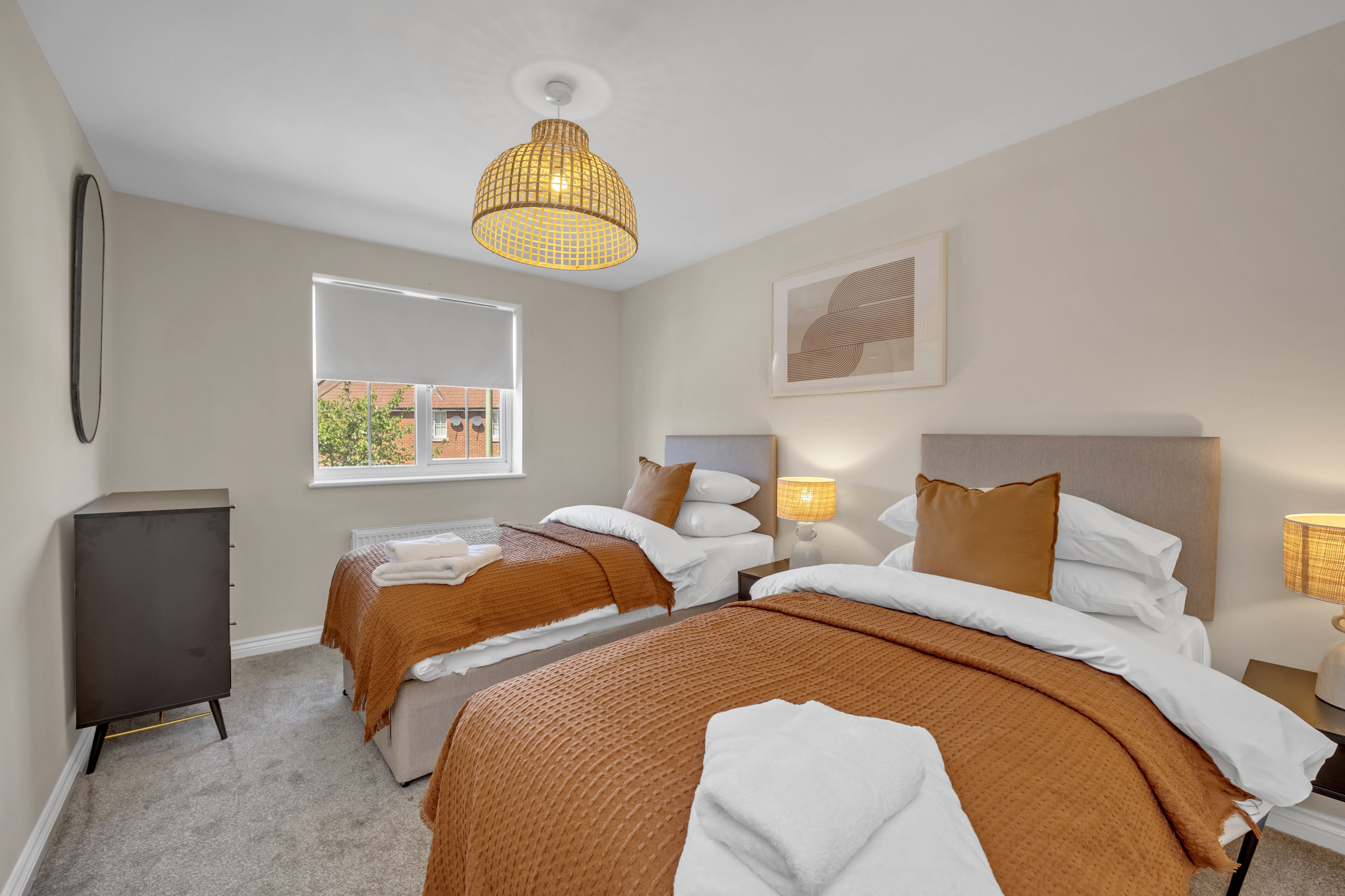 Hotellihuone, jossa on kaksi sänkyä, vaatekaappi, ikkuna, josta on näkymä, ja riippuvalaisin.