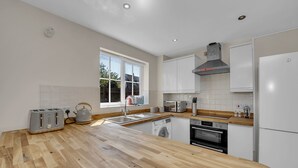 A modern kitchen with wooden countertops, a built-in oven, a sink, and a window providing natural light.