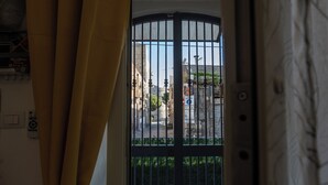 A view through a metal gate with a street and buildings in the background. - Al Castello-Independent house- Holiday home in Catania (Catania)