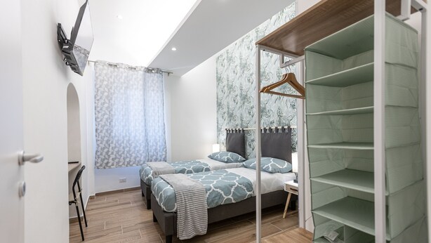 A bedroom with two beds, a desk, and a walk-in closet. - Al Castello-Independent house- Holiday home in Catania (Catania)