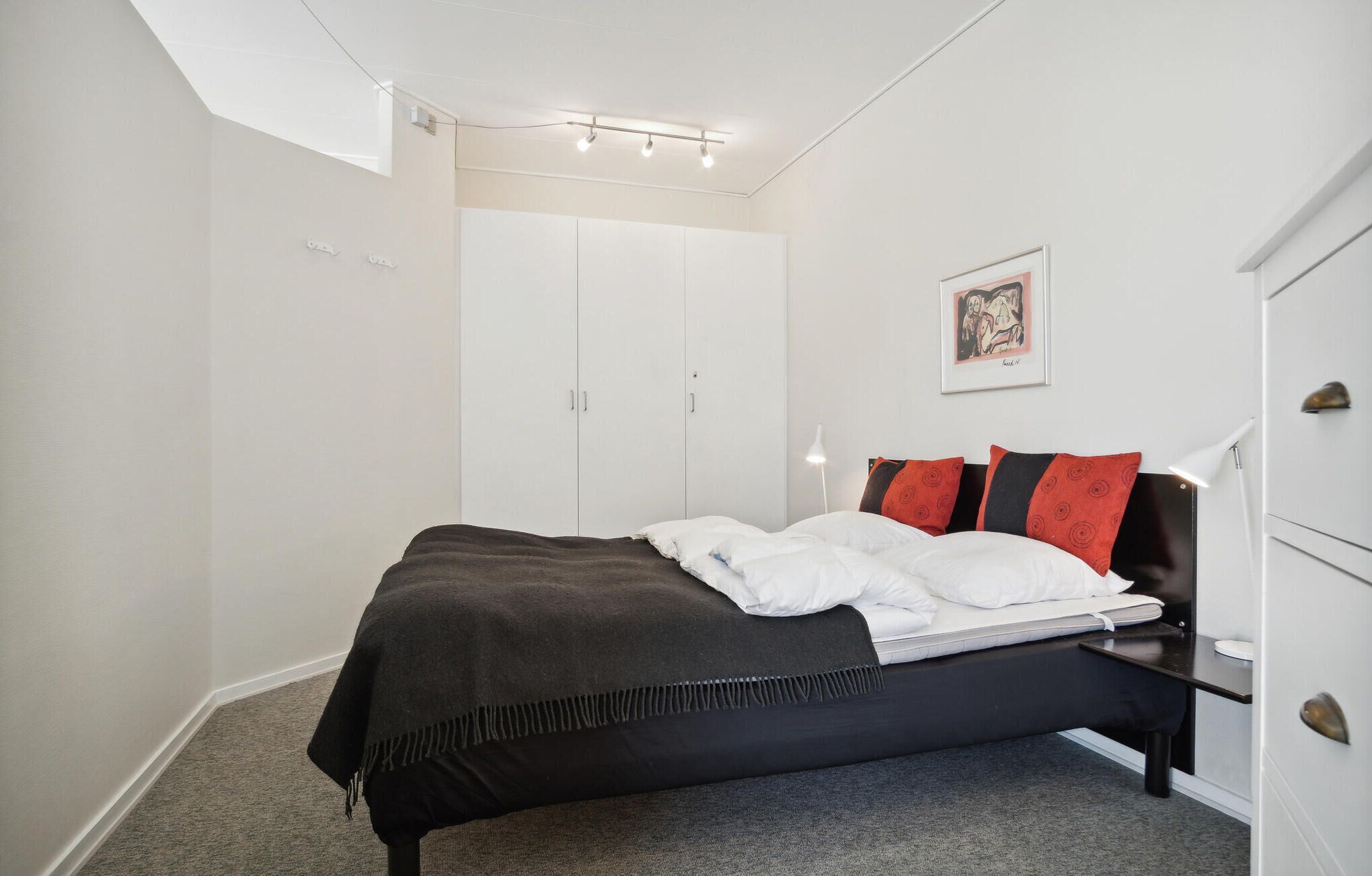 Una camera da letto con un letto, un armadio, un quadro appeso alla parete e una lampada a soffitto.