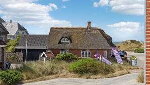 A traditional thatched-roof house with a stone wall, a small garden, and a clear view of the sea. - 2 bedroom nice apartment in Fanø (Fanø)