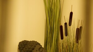 A Buddha statue next to a potted plant with tall grasses and cattails. - Asia Dreieck Pension Zimmer (Lauterecken)