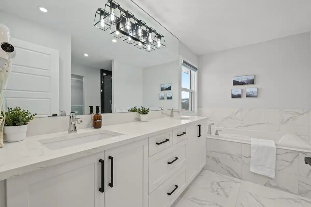 Une salle de bain moderne avec un meuble-lavabo blanc, un grand miroir et un mur en marbre.