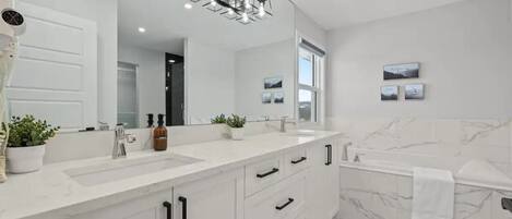 Une salle de bain moderne avec un meuble-lavabo blanc, un grand miroir et un mur en marbre.