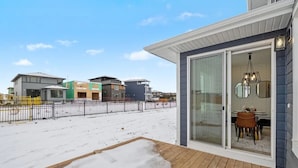 Il s’agit d’une propriété résidentielle dotée d’un patio couvert, d’un coin repas avec une table et des chaises, et offrant une vue sur les maisons voisines.