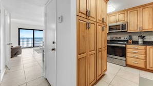 A modern kitchen with wooden cabinets, stainless steel appliances, and a view to the outside. - Oceanfront Charmer (Ormond Beach)