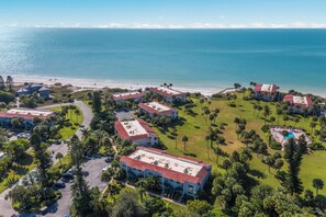 A resort with multiple buildings, a pool area, and a beach view.