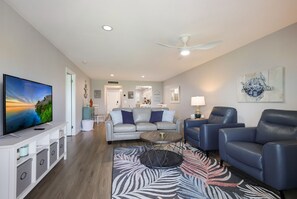 A modern living room with a flat-screen TV, grey leather sofas, a coffee table, and a zebra-patterned rug. - Beachfront Bliss: 2/2 with Stunning Gulf Views! (Longboat Key)